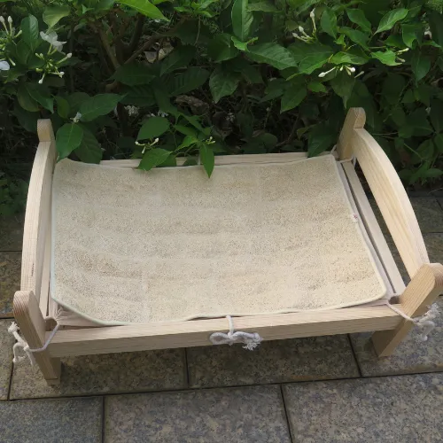 A wooden pet bed with a loofah mat stretched across the frame