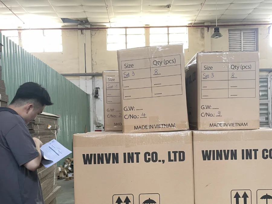 WINVN INT staff member checking paperwork against a stack of cartons